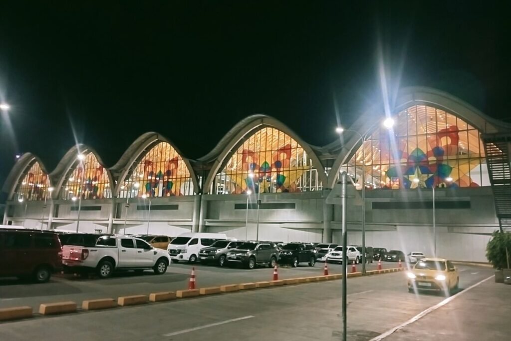 Mactan-Cebu International Airport Terminal 2 illuminated at night, showing its distinctive curved roof and entrance.