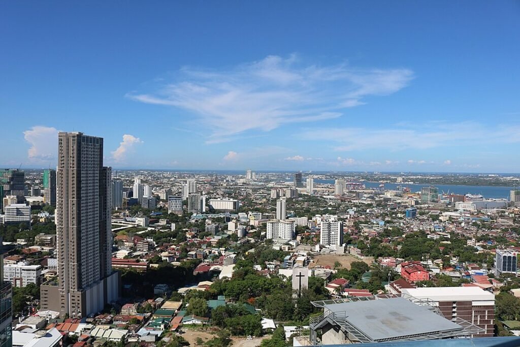 Panoramic view of Cebu City's skyline, high-rise hotels and surrounding urban landscape under a blue sky.