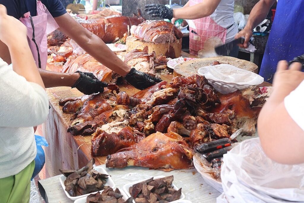 Traditional Cebu lechon being chopped and served at a food stall in Talisay, Cebu.