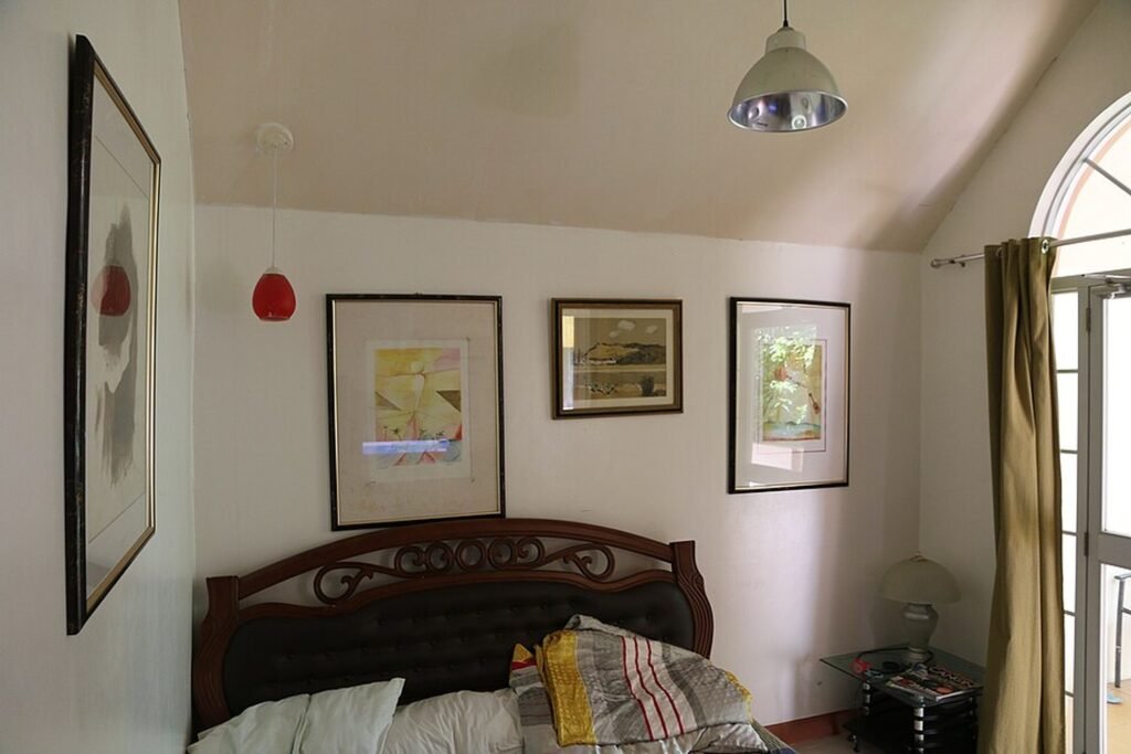 Guest room at Haruhay Resort on Mactan Island, Cebu, featuring a wooden bed, framed artwork and natural light.